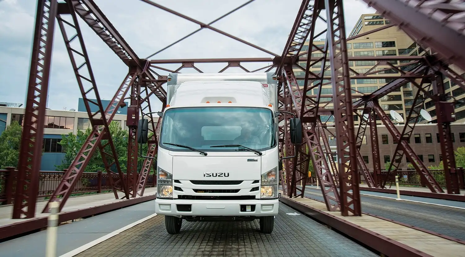 Isuzu NPR medium-duty truck driving across a bridge