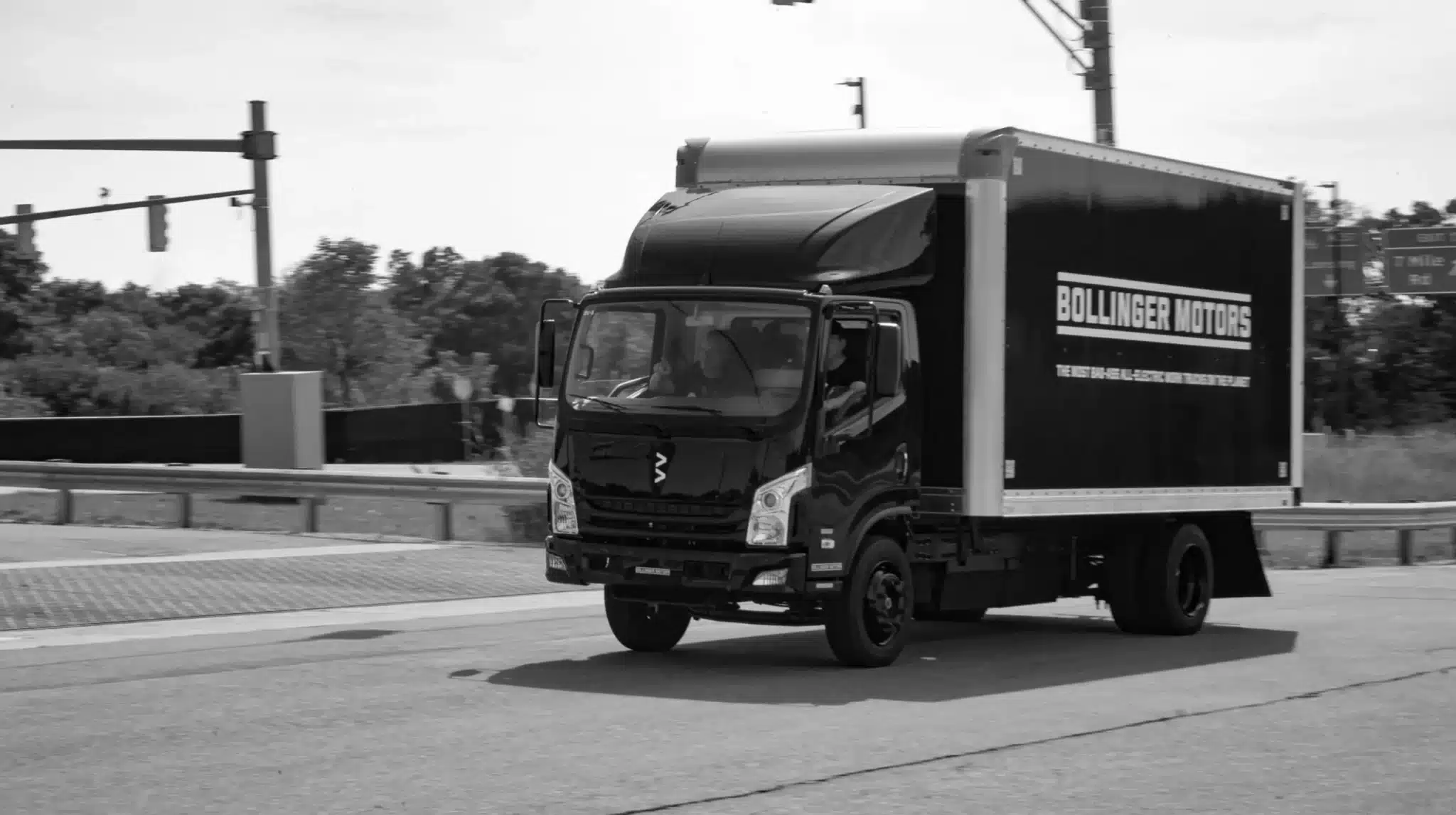Black Bollinger B4 box truck turning down a road