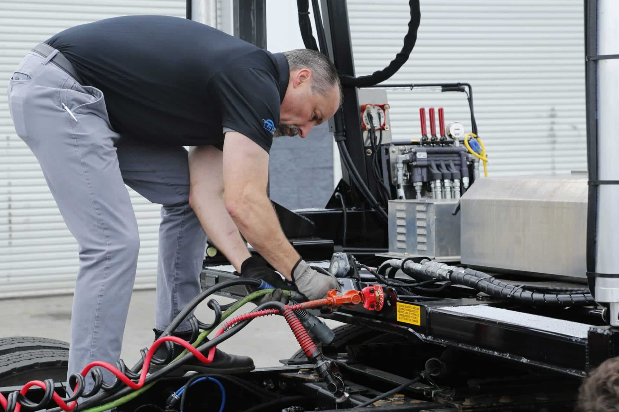 Auto transport team member hooking up a car carrier trailer to a auto hauler