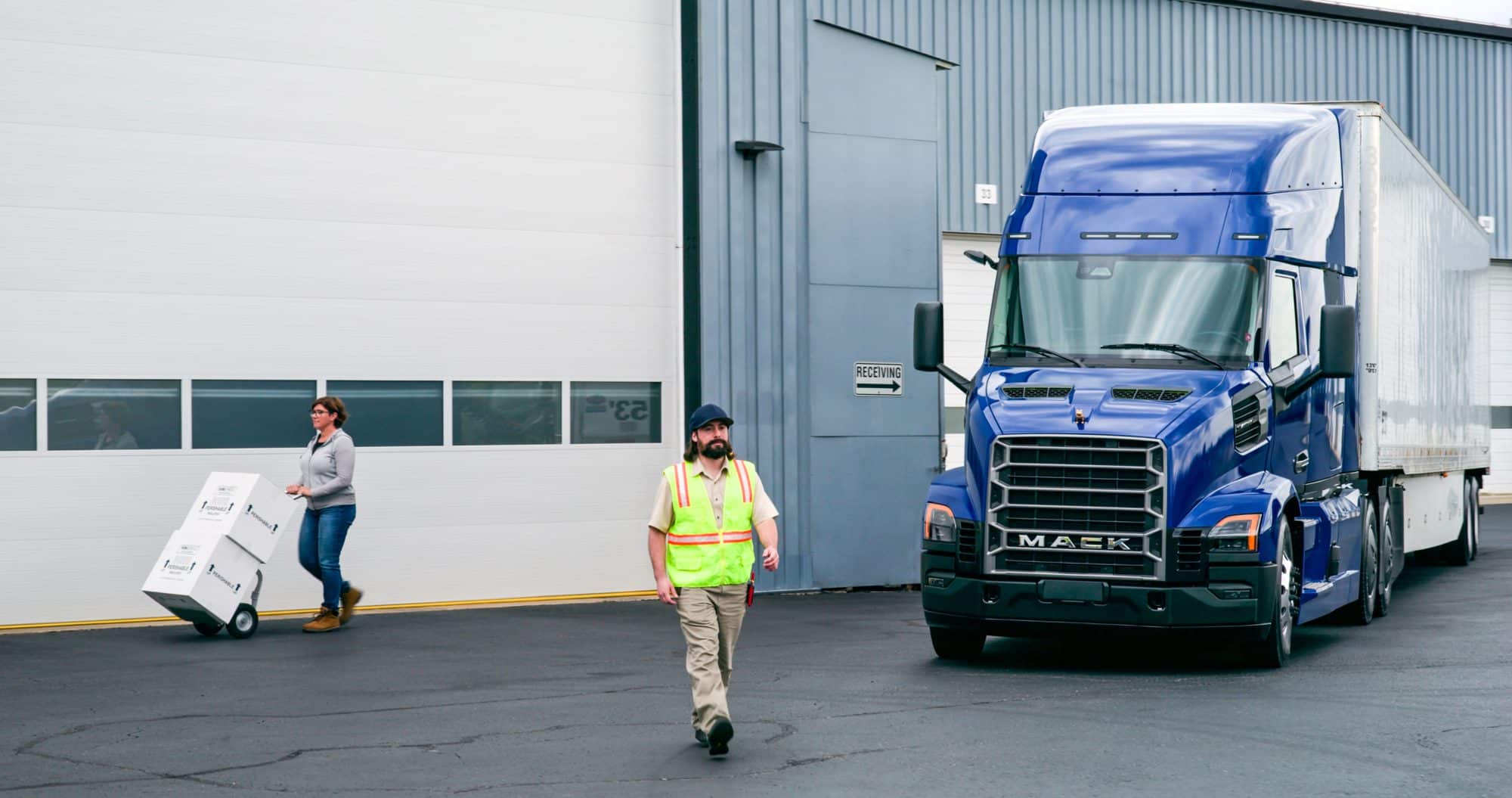 All-new blue Mack Anthem parked next to a building and the driver is walking in front
