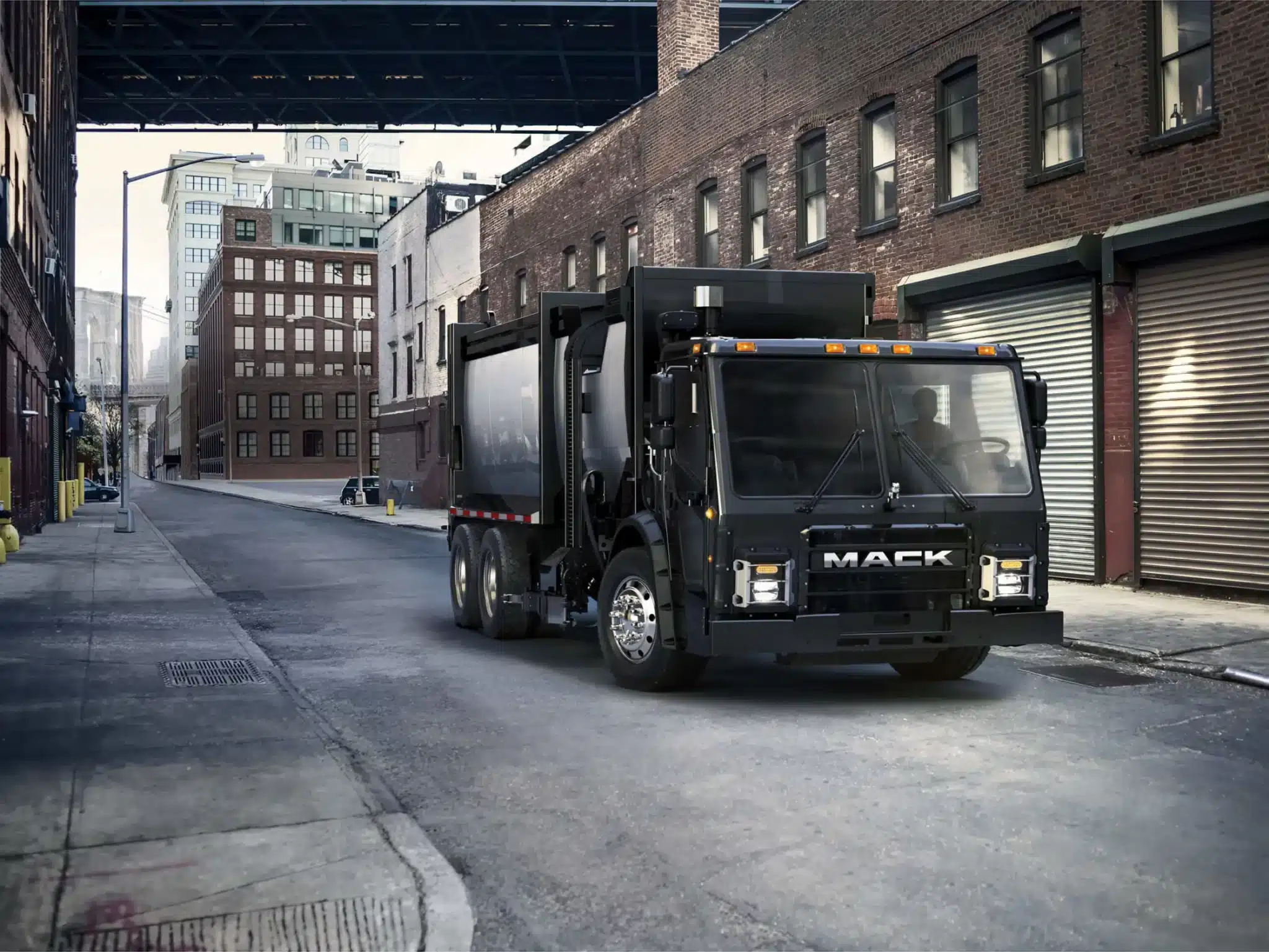 Black Mack LR refuse truck driving through an ally