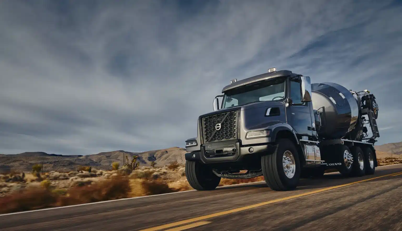 Grey Volvo VHD with a tank body driving on the road in the desert.