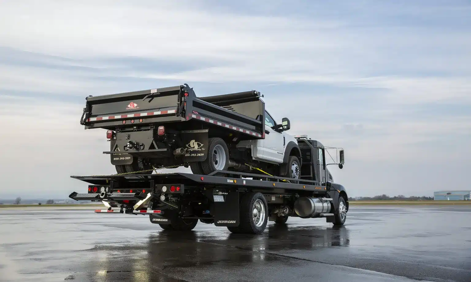 Jerr-Dan car carrier hauling another truck in the middle of a parking lot.