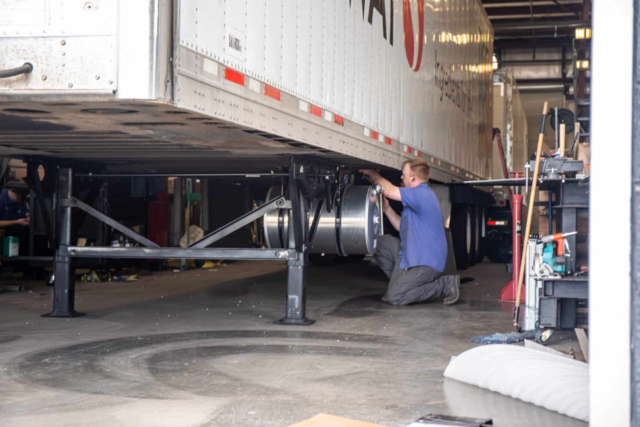 Trailer technician bending down to fix the bottom of a dry van trailer.