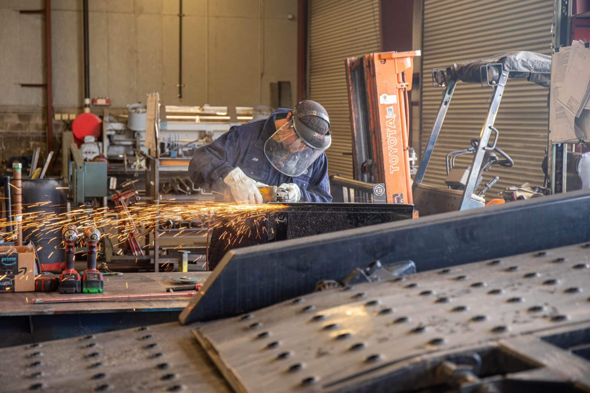 Technician in a service department welding a piece of a trailer.
