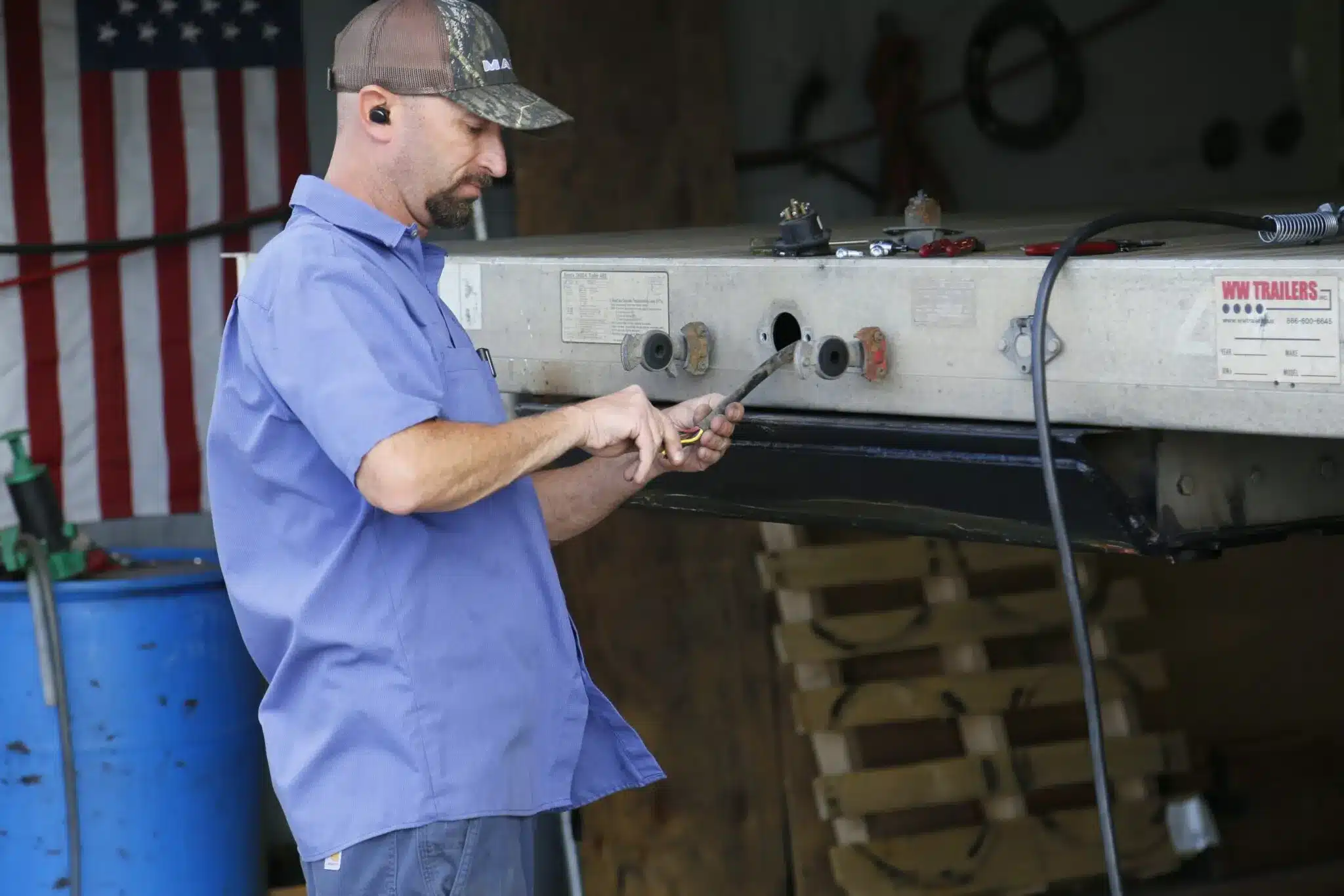 Trailer technician fixing the wiring on the back of a flatbed trailer.
