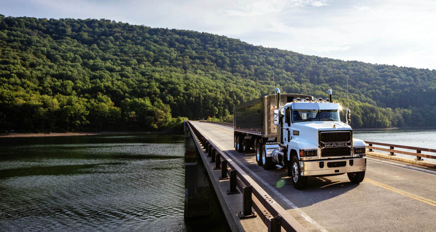 White Mack Pinnacle driving across a bridge over water with trees in the background