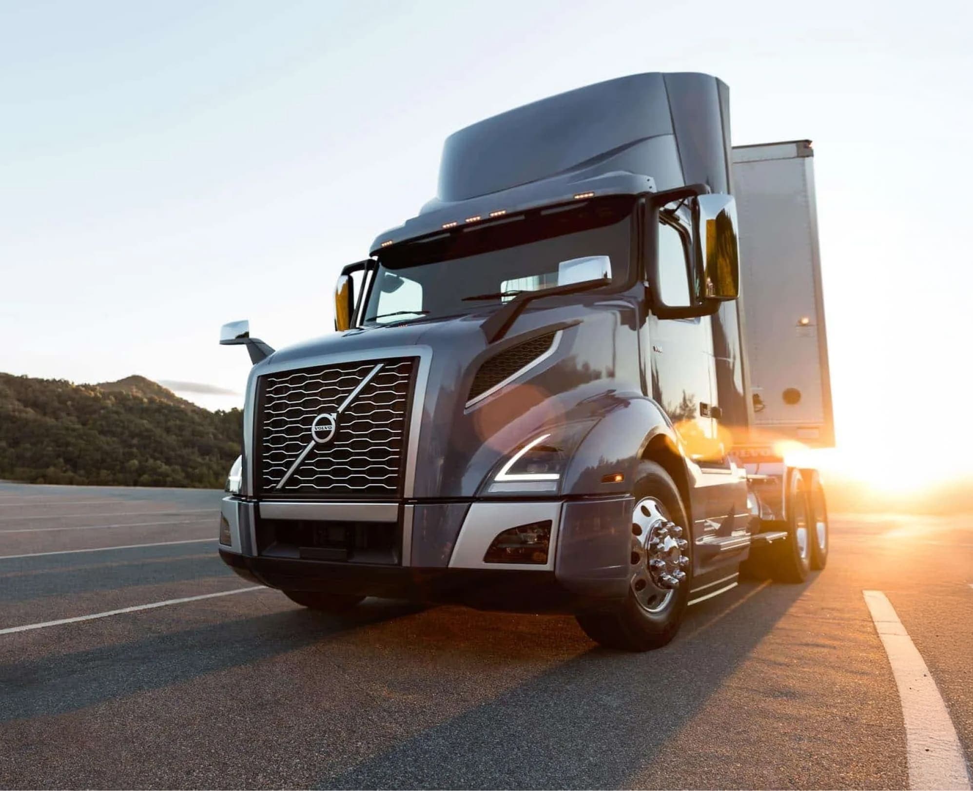 Volvo VNL 300 day cab truck driving on the road with the sun behind it.