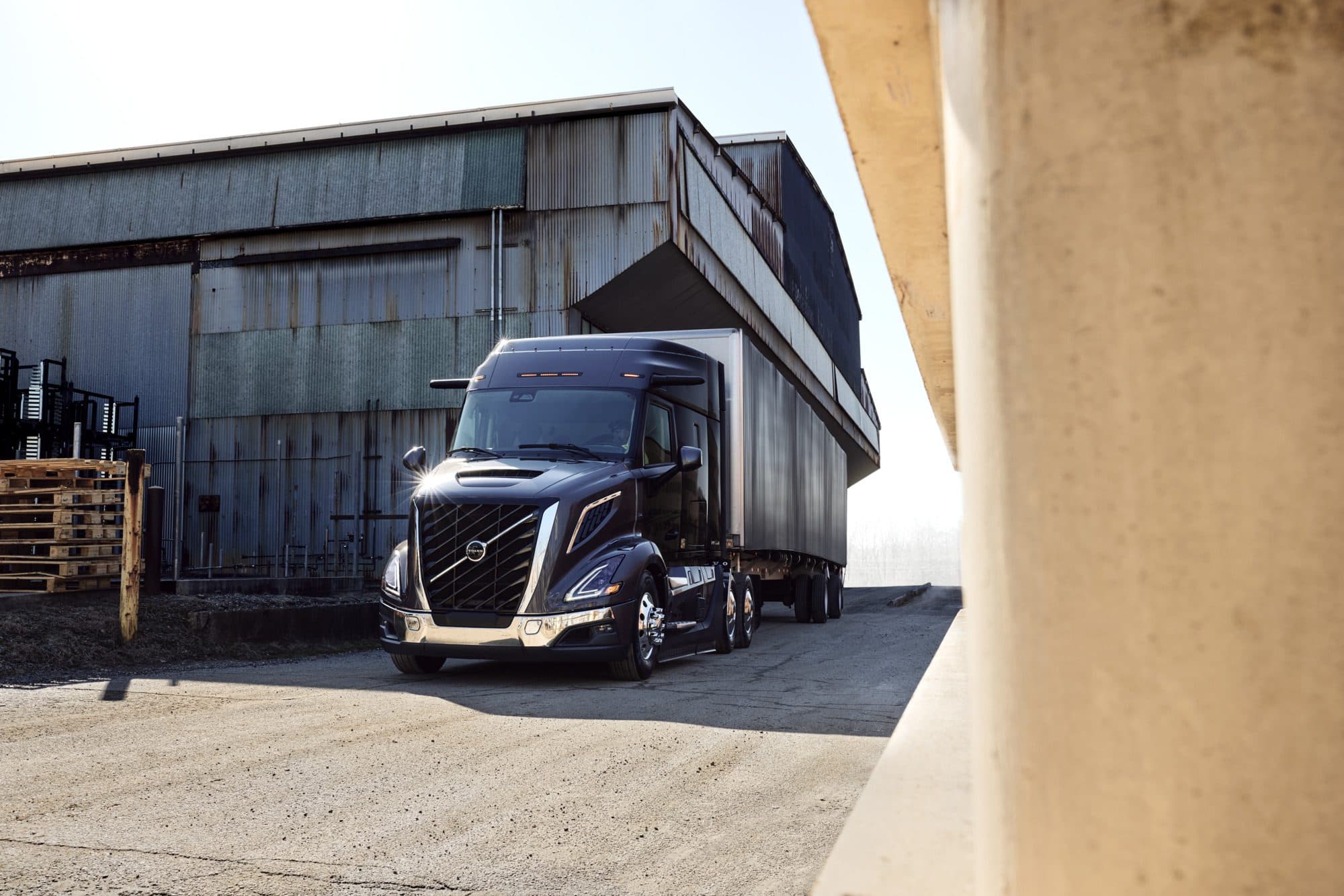 Blue all-new Volvo VNR 440 parked next to an agricultural building