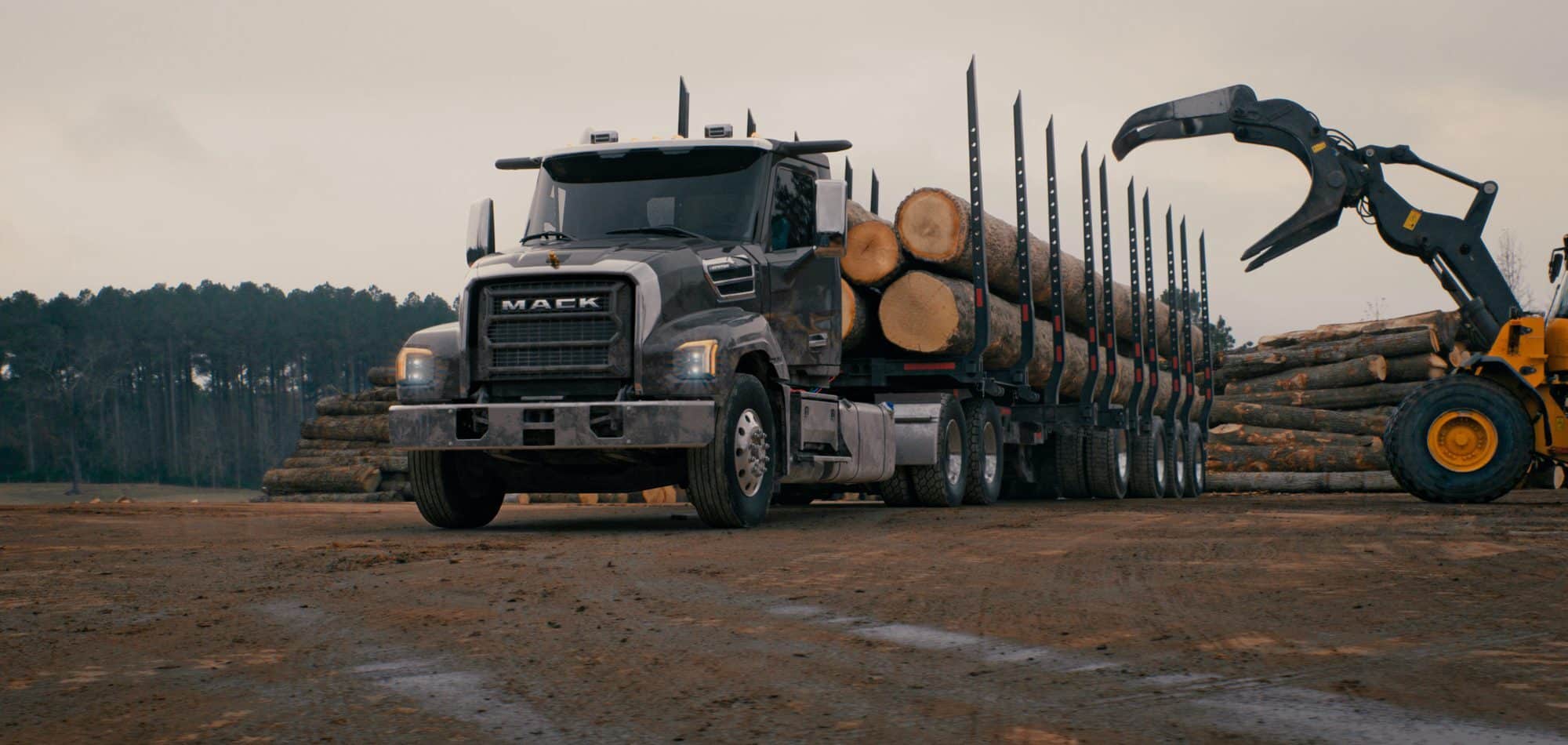 Black Mack Keystone with logs in the trailer while equipment is grabbing logs from the trailer